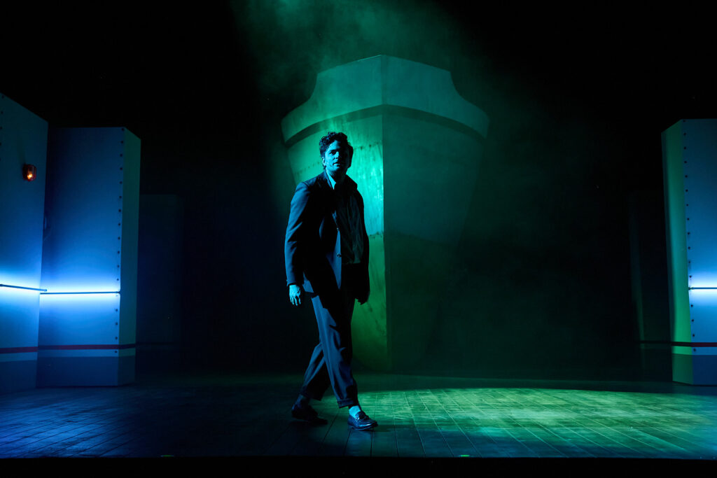 W centrum zdjęcia widzimy aktora w ruchu. W tle wyłania się dziób statku.